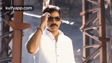a man wearing sunglasses and a white shirt is standing in a building .