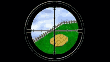 a sniper scope shows a green field and a fence in the distance