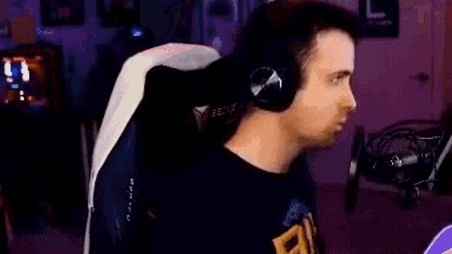 a man is sitting in a gaming chair wearing headphones and making a funny face .
