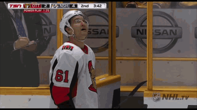 a hockey player wearing number 61 stands in front of a nissan logo
