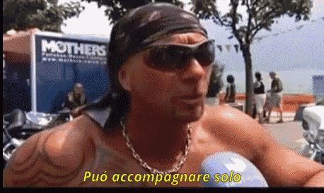 a man wearing sunglasses and a bandana says può accompagnare solo in front of a mothers truck