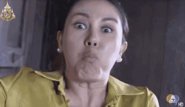 a woman in a yellow shirt is making a funny face in front of a tv screen that says hd