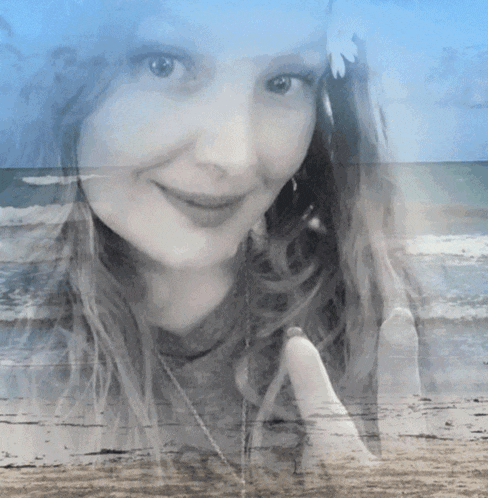 a black and white photo of a woman with a flower in her hair and a beach in the background