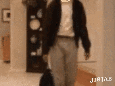 a man is walking down a hallway with a suitcase and a backpack .