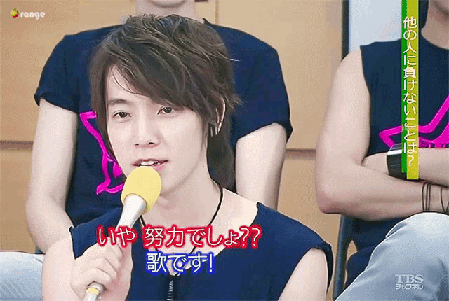 a young man is holding a microphone with a tbs channel advertisement behind him