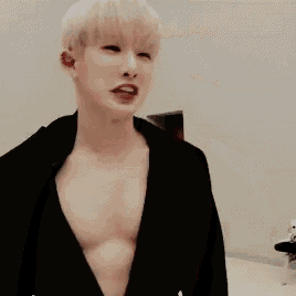 a young man is standing in a room without a shirt on and looking at the camera .