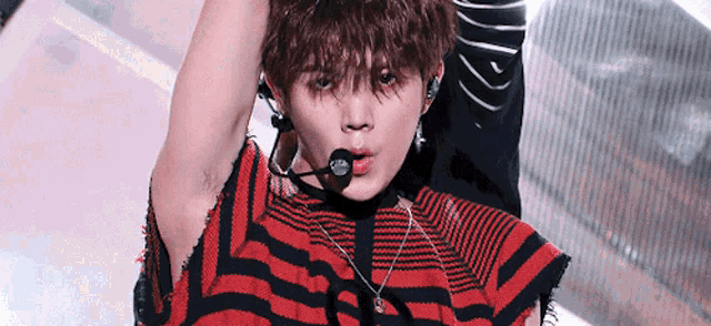a close up of a person wearing a red and black striped shirt and a microphone in their mouth .
