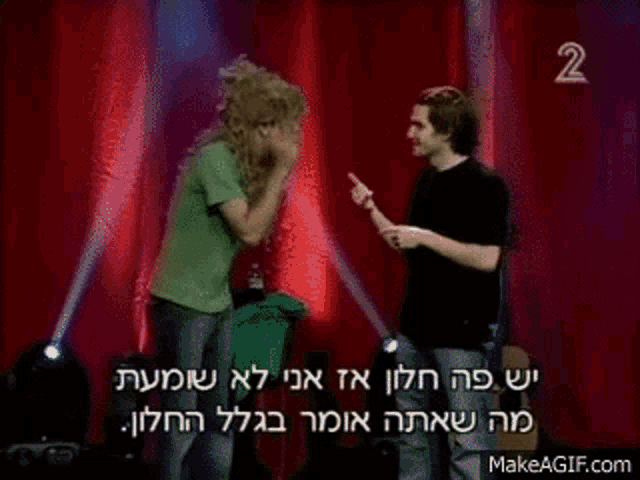 two men are standing next to each other on a stage and one of them is pointing at the other .