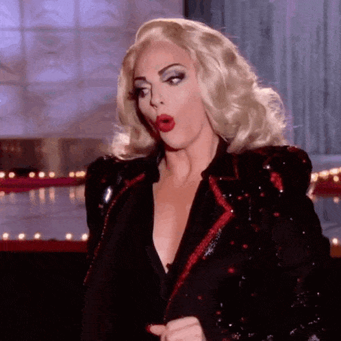 a woman in a wig and a black jacket is making a funny face .