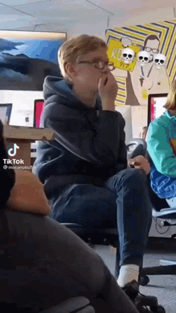 a boy wearing glasses is sitting on a chair in a classroom .