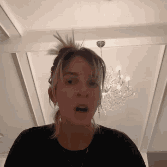 a woman making a funny face with a chandelier behind her