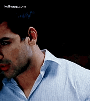 a close up of a man 's neck and ear in a blue shirt .