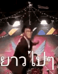 a man in a suit is dancing on a stage with a drum set .