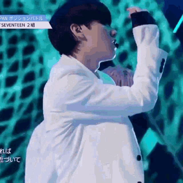 a man in a white jacket is singing into a microphone on a stage ..