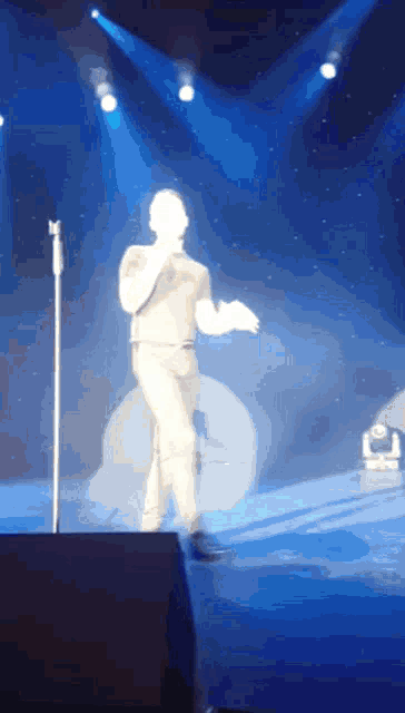 a man singing into a microphone on stage