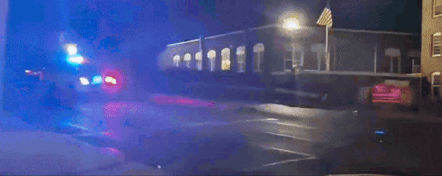 a police car is driving down a street at night with its lights on
