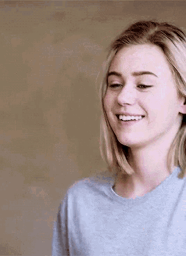 a close up of a woman 's face smiling and wearing a grey shirt .
