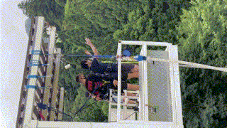 a man wearing a red and black vest with the letter r on it is jumping off a bungee cord