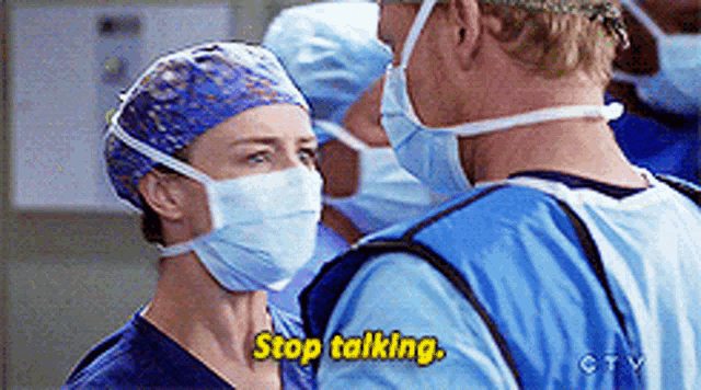 a man and a woman wearing surgical masks are talking to each other