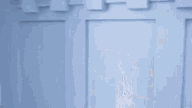 a man in a robe is standing in front of a blue door .