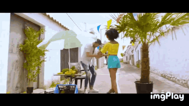 a man and a woman are standing under an umbrella on a street with imgplay written on the bottom of the screen