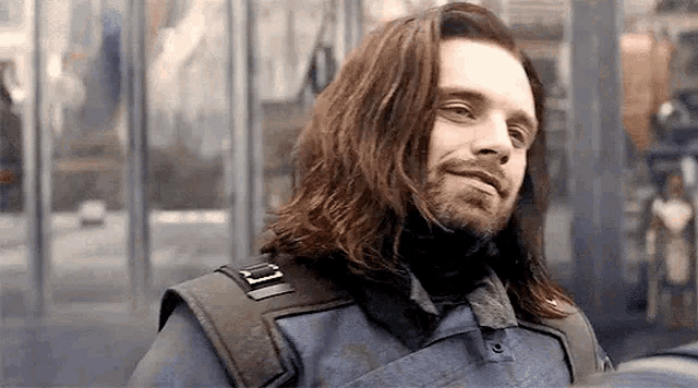 a man with long hair and a beard is wearing a military uniform and smiling .