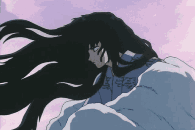 a woman with long black hair is laying on a bed