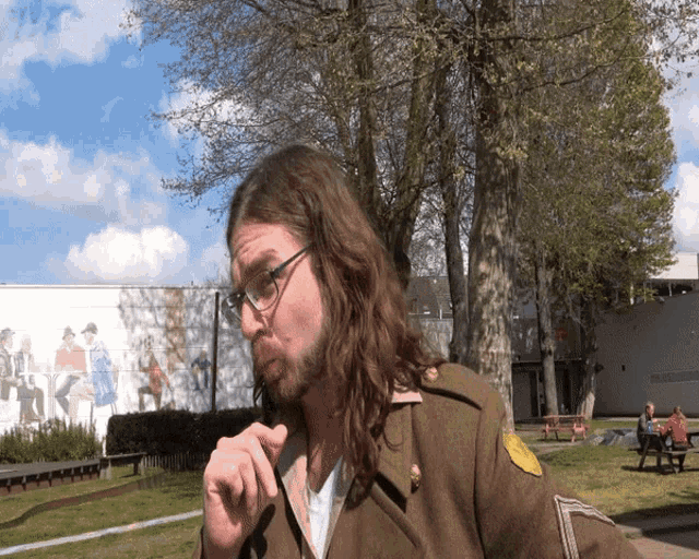 a man wearing glasses and a military uniform stands in front of a building that says ' amsterdam museum '