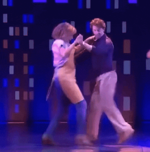 a man and a woman are dancing on a stage