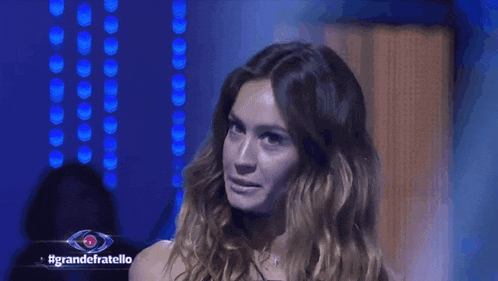 a woman is standing in front of a sign that says grande fratello