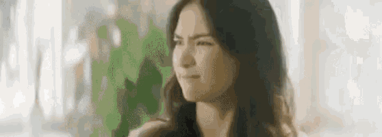 a woman is making a funny face and looking at the camera .