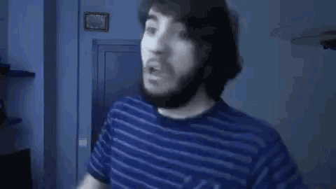a man with a beard is making a funny face while wearing a blue striped shirt .