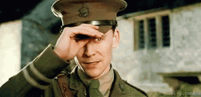 a man in a military uniform is covering his eyes with his hands .
