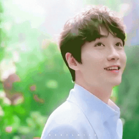 a young man wearing a blue shirt is smiling and looking up .