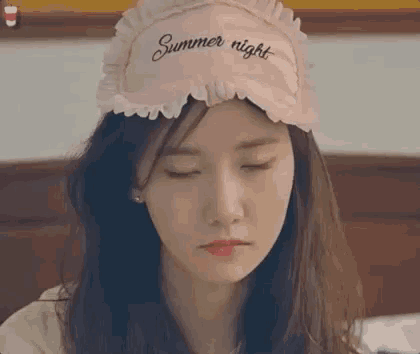 a young woman wearing a pink sleep mask with the words summer night on it .