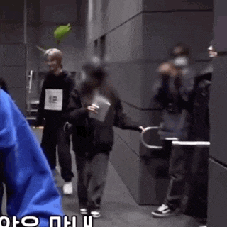 a group of people are walking down a hallway and one of them is wearing a shirt with the number 12 on it .
