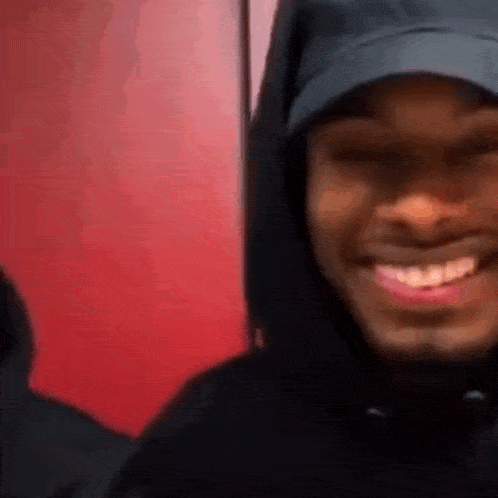 a man wearing a black hat and a black hoodie is smiling .