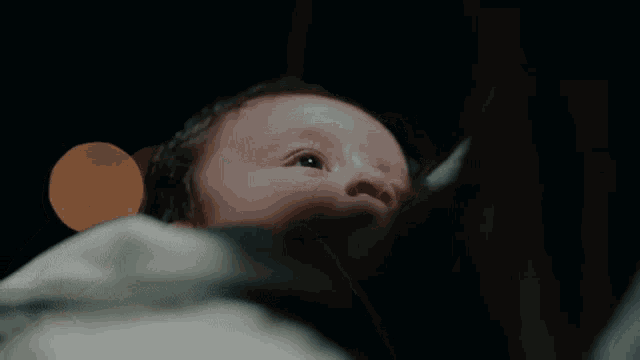 a close up of a baby 's face with a dark background