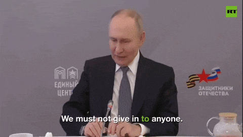 a man in a suit and tie says " we must not give in to anyone " while sitting at a table
