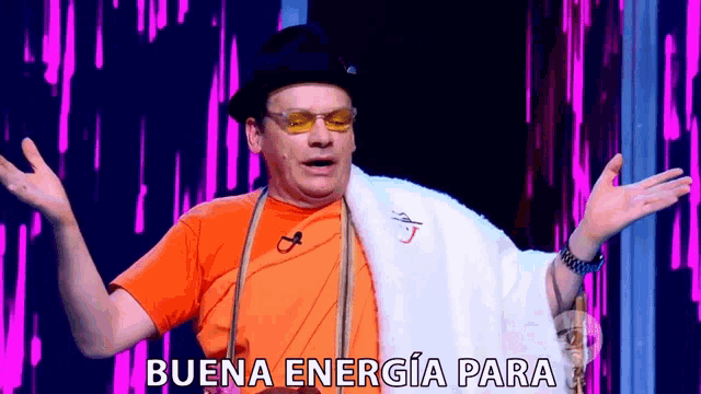 a man wearing a hat and glasses is standing on a stage with his arms outstretched and says buena energia para