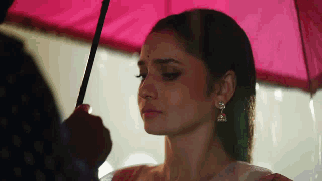 a man is holding an umbrella over a woman 's head in the rain .