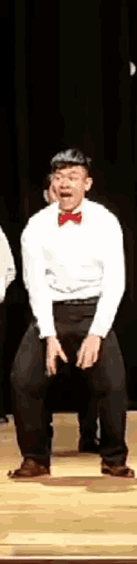 a man in a tuxedo and bow tie is dancing on a stage