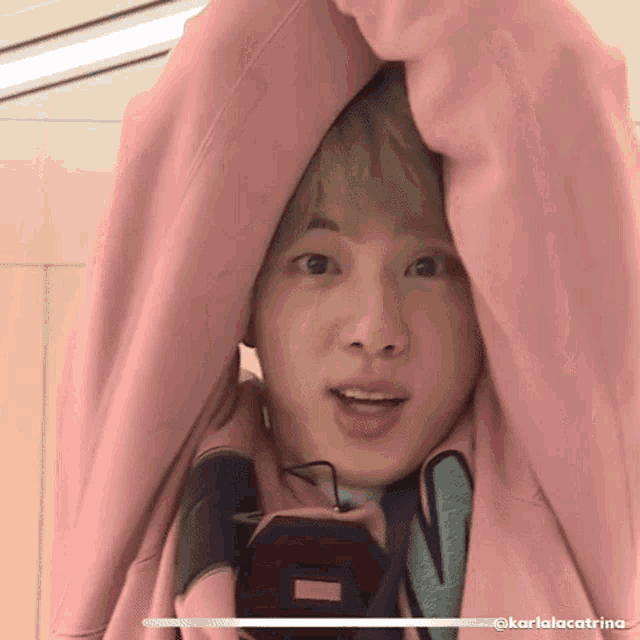 a close up of a person 's face wearing a pink hoodie