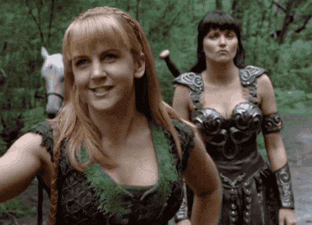 a woman in a green top stands next to a woman in a silver top
