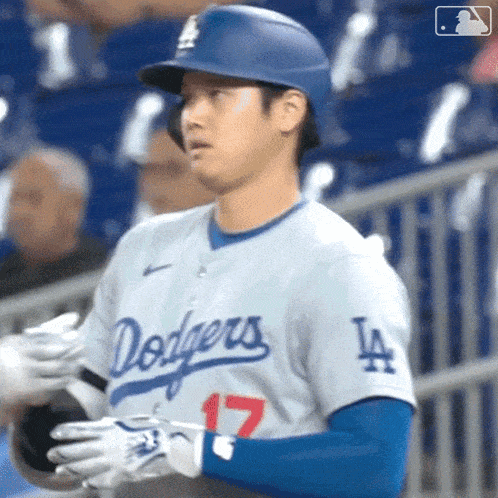 a baseball player wearing a dodgers jersey holds his bat