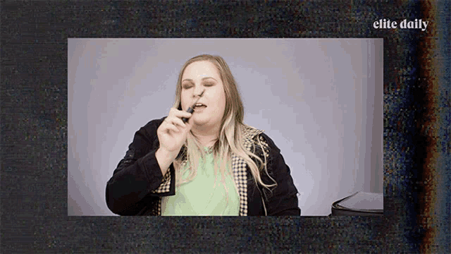 a video of a woman applying lipstick with the words elite daily on the bottom right