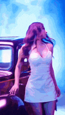 a woman in a white dress standing next to a black car
