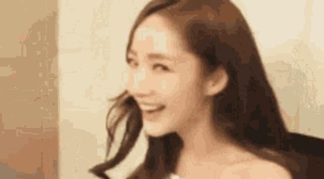 a close up of a woman 's face with long hair smiling .