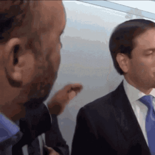 two men in suits and ties are talking to each other