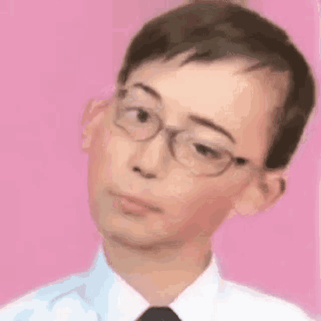 a young boy wearing glasses and a white shirt is making a funny face .